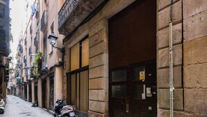 Una calle estrecha con una moto estacionada, un edificio con una entrada oscura y una farola.