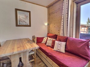 Un lit en bois avec une literie rouge, une table en bois et une affiche encadrée accrochée au mur.