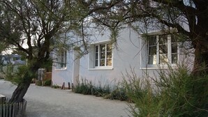 Una casa con entrada pavimentada, cerca de madera y abundante arbolado.