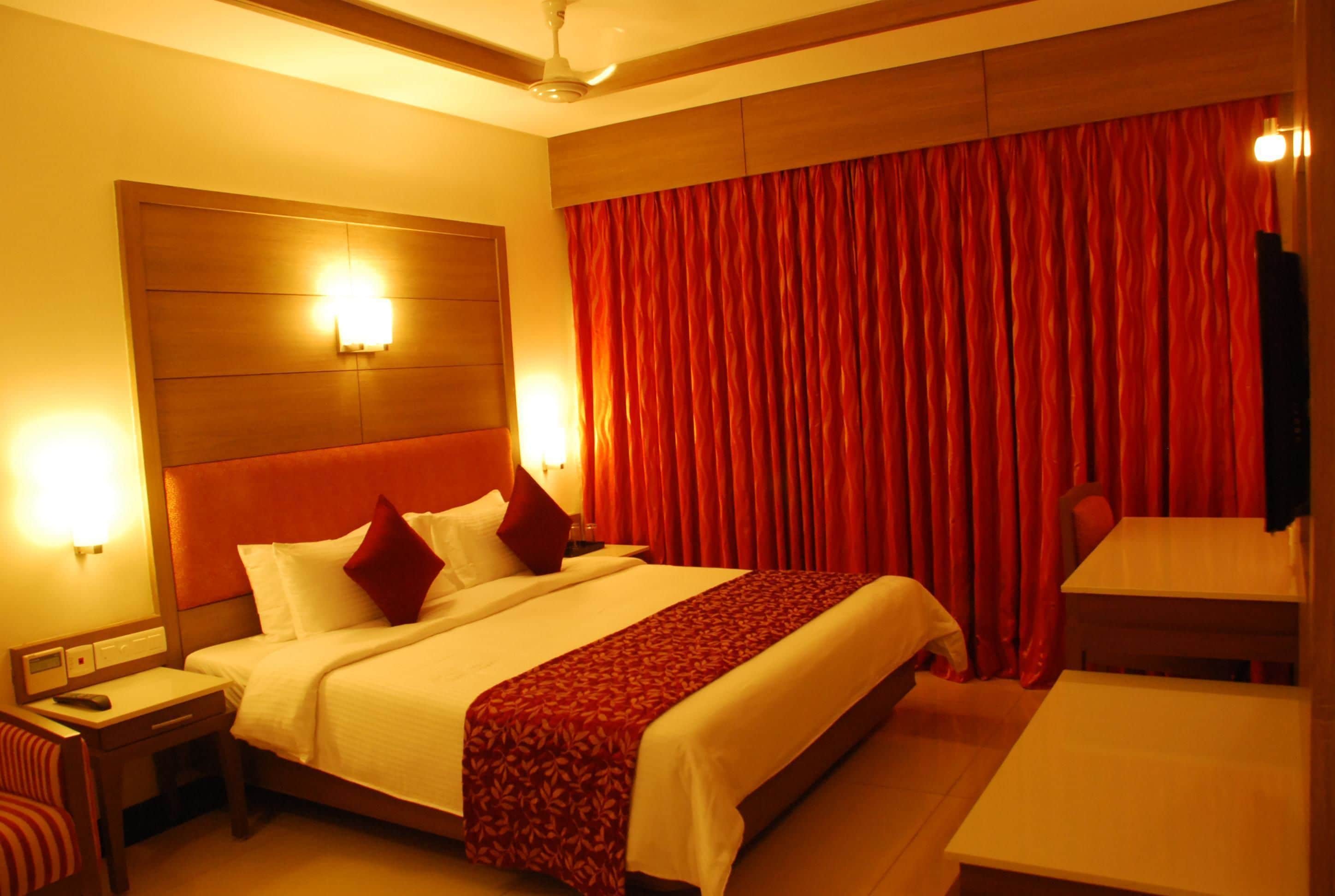 A hotel room with a large bed, a desk, and a dining table.