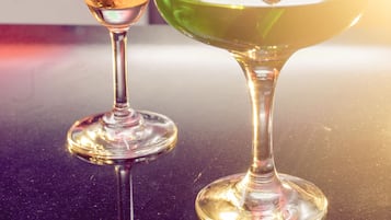 Two martini glasses on a reflective surface with a blurred background.