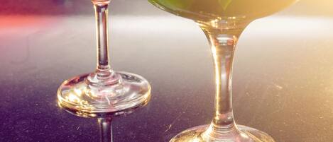 Due bicchieri di martini su una superficie riflettente, con sfondo sfocato.