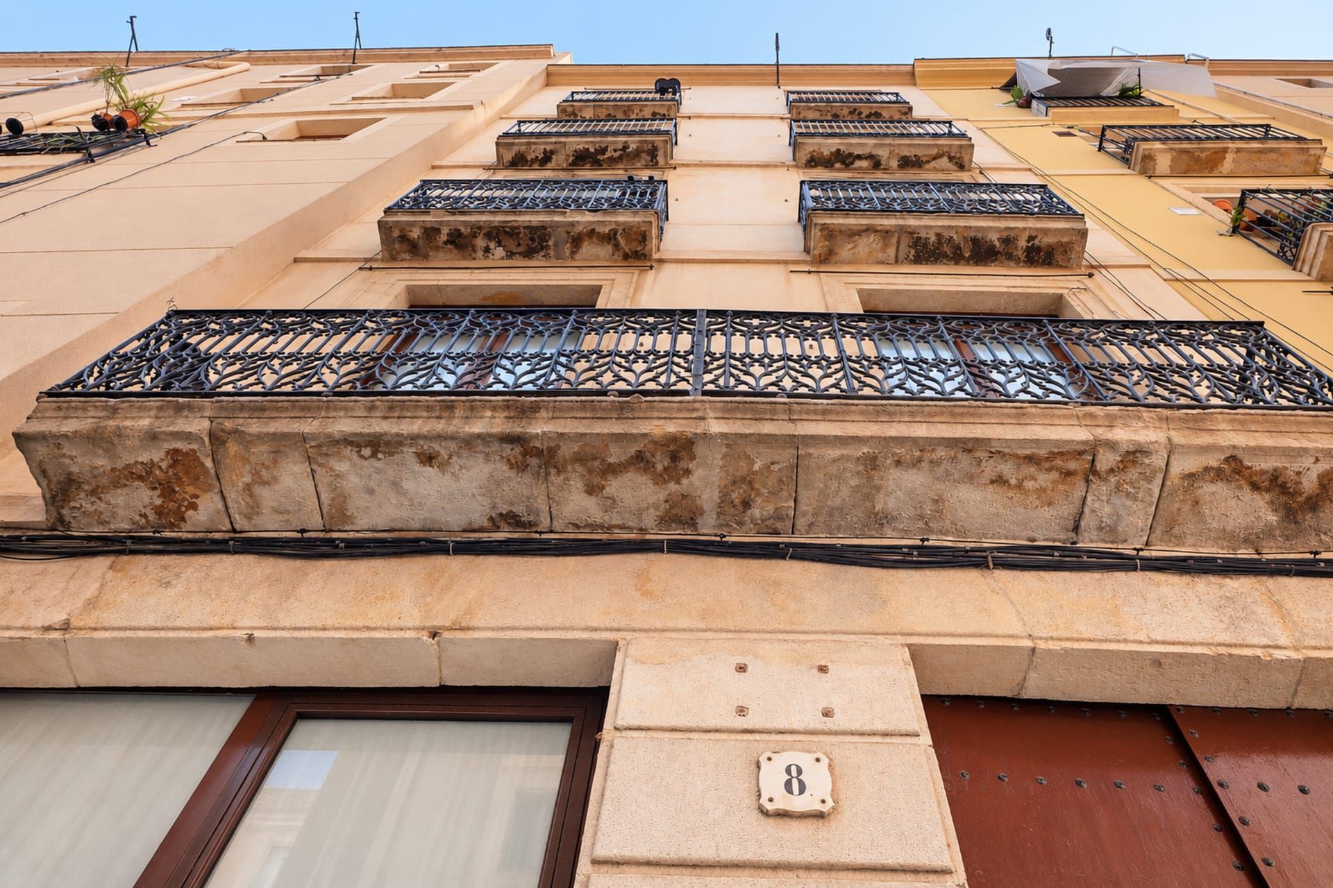 A building with multiple balconies, each with a metal railing and a small window.