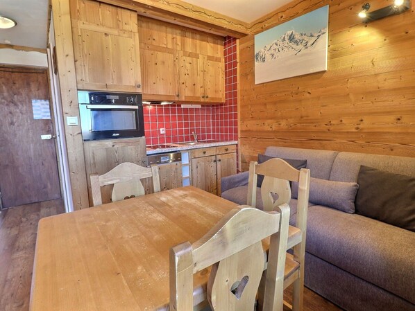 A wooden interior with a kitchen, dining table, and sofa.