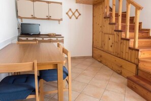 A wooden dining table with chairs, a television on a stand, a wooden staircase, and a wall-mounted shelf. - M035 - Marcelli, three-room apartment with terrace and a / c (Marcelli)
