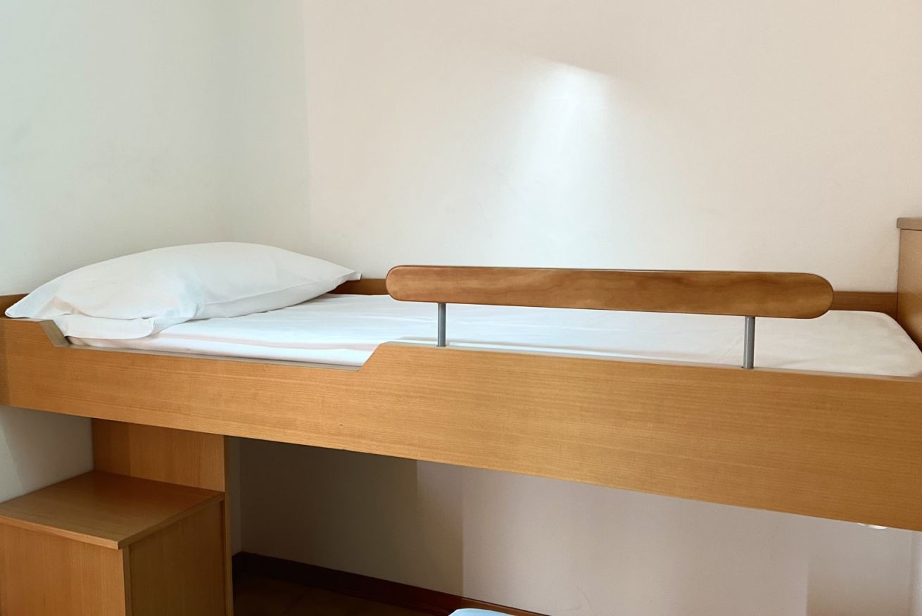 A bunk bed with a wooden frame and white bedding.