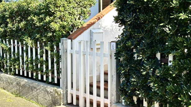 A white gate with a wooden handrail, a white picket fence, and green foliage. - M035 - Marcelli, three-room apartment with terrace and a / c (Marcelli)