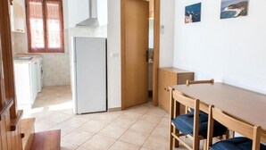 A compact kitchen with a refrigerator, a wooden dining table with chairs, and a bench. - M035 - Marcelli, three-room apartment with terrace and a / c (Marcelli)