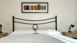 A neatly made bed with white linens, a black metal headboard, and a framed artwork above. - M035 - Marcelli, three-room apartment with terrace and a / c (Marcelli)