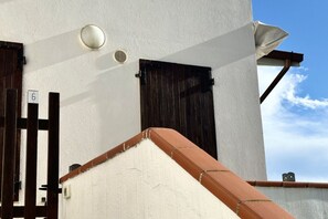 A white building with a brown door, a window, and a small circular light fixture.