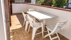 A patio with a white table and chairs, a tiled floor, and a view of greenery. - M035 - Marcelli, three-room apartment with terrace and a / c (Marcelli)