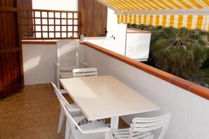 A small balcony with a white table and chairs, a wooden fence, and a yellow-striped awning. - M035 - Marcelli, three-room apartment with terrace and a / c (Marcelli)