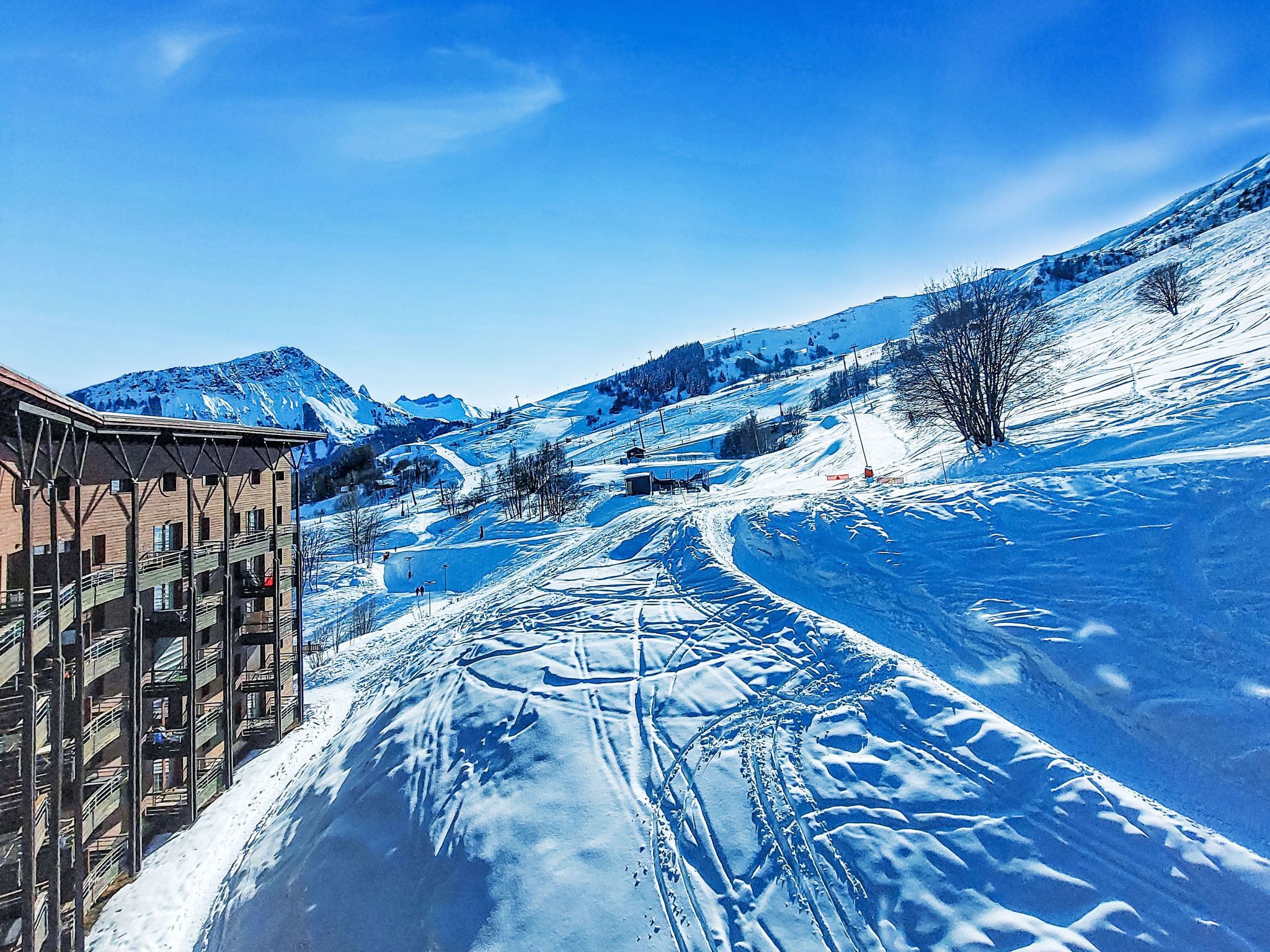 A snow-covered ski slope with a building on the left.