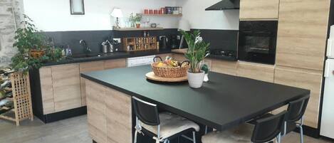 A modern kitchen with a central island, wooden cabinets, and a built-in oven.