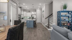 Una cocina moderna con una isla central, muebles blancos y una pared azul de acento.