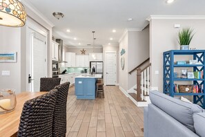 A modern kitchen with white cabinets, a blue island, and a central island with a sink.