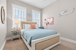 A bedroom with a bed, a nightstand, a lamp, and wall art.