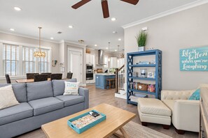 Een moderne woonkamer met een grijze bank, een beige fauteuil, een houten salontafel en een boekenkast.