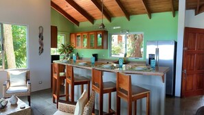 Una cucina con soffitto in legno, una grande isola con sgabelli da bar e un frigorifero.