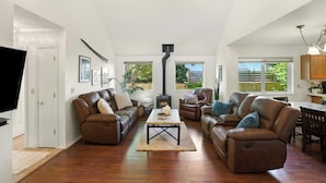 A spacious living room with leather sofas, a central coffee table, and a fireplace. - Coastal Place - BEST location in Downtown (Anchorage)