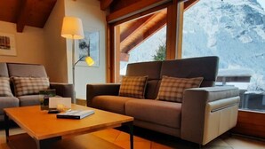 A cozy living room with a sofa, a wooden coffee table, and a lamp. - Chalet Abendrot apARTments by Interhome (Grindelwald)