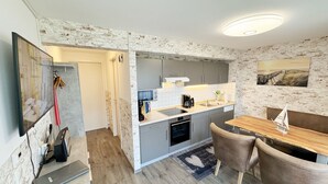 A modern kitchen with grey cabinets, a wooden dining table, and a small sailboat model. - Apartment 06 with balcony and view of the Bodden - MR: Haus Inselperle with view of the (Mönchgut)