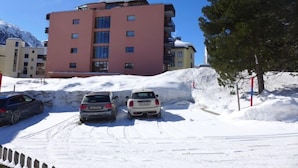 A parking area with three cars parked in front of a building with a red facade. - Chesa Corvatsch 111 - Champfer by Interhome (Champfer)