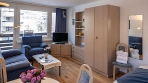 A modern living room with a sofa, a coffee table, a TV, and a wardrobe. - Chesa Corvatsch 111 - Champfer by Interhome (Champfer)