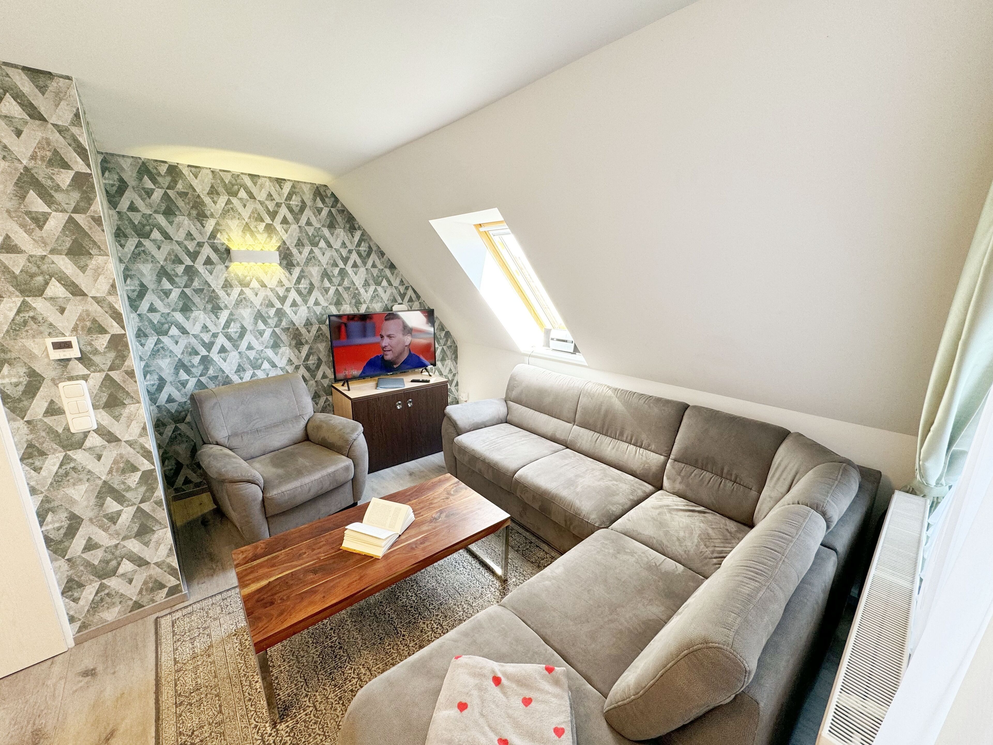 A modern living room with a sofa, armchairs, a coffee table, and a TV.