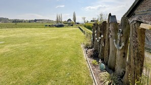 Un campo cubierto de hierba con una valla de madera y una casa al fondo.