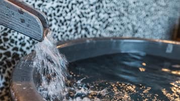 A wooden bucket with water flowing into a metal basin.