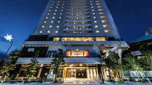 Un hotel alto con diseño moderno, que destaca por su entrada principal y un cartel que dice "APART HOTEL".
