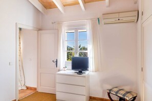 A room with a window, a desk with a computer, a chair, and an air conditioning unit. - Family Country House with Pool in Andratx (Port Andratx)