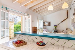 A kitchen with a blue countertop, a television, and a dining area with a table and chairs. - Family Country House with Pool in Andratx (Port Andratx)