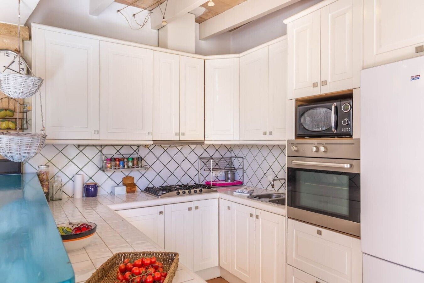 A kitchen with white cabinets, a gas stove, a microwave, and a refrigerator.