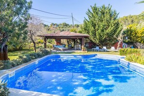 A swimming pool with a pergola and lounge chairs, surrounded by greenery and trees. - Family Country House with Pool in Andratx (Port Andratx)