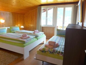 A room with two beds, wooden walls, and a large window.