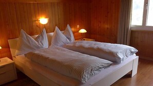 Ein Doppelbett mit weißer Bettwäsche und gestreiften Kissen in einem Zimmer mit Holzwänden und zwei Nachttischlampen.