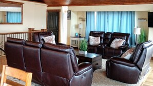 A spacious living room with a high ceiling and wooden beams, furnished with leather sofas and a coffee table. - Amazing view - Lake House Retreat with Mountain Cabin Warmth (Garden City)