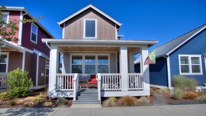 A two-story house with a front porch, a small outdoor seating area, and a flag. - Ocean Adventure - Oyhut Bay Seaside Village (Ocean Shores)