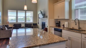 A modern kitchen with granite countertops, white cabinetry, and a central island. - Ocean Adventure - Oyhut Bay Seaside Village (Ocean Shores)