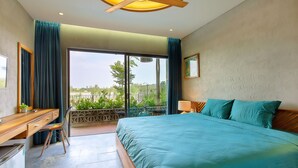 Un dormitorio con cama, escritorio, silla y vistas al exterior.