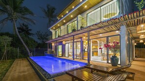 Una casa moderna con piscina, mobiliario de exterior y un patio cubierto.