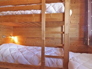 A bunk bed with wooden walls and a wall-mounted light fixture.