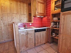 A kitchen with wooden cabinets, a Bosch dishwasher, and a red tiled backsplash.