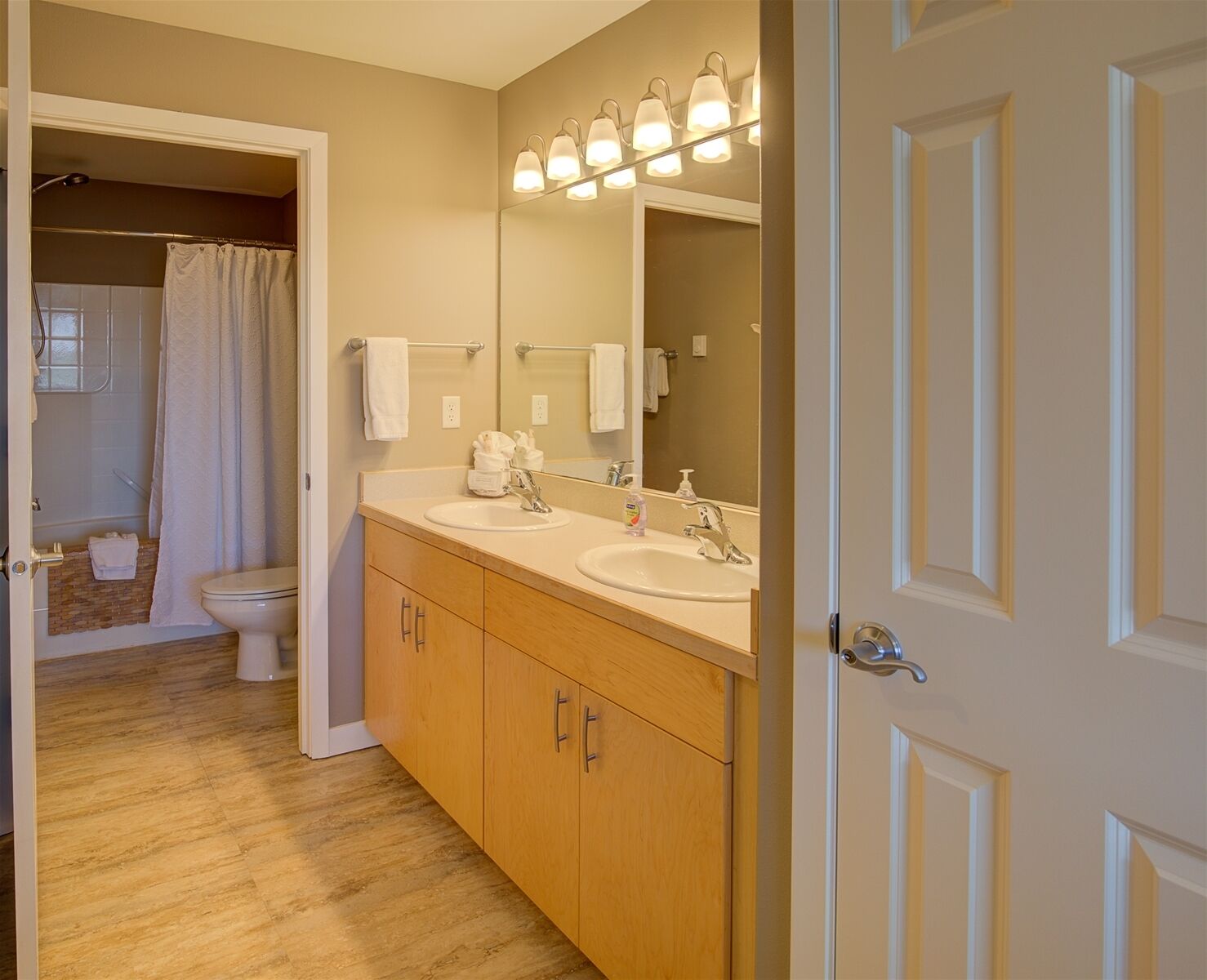 A bathroom with two sinks, a toilet, and a shower.