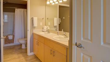 A bathroom with two sinks, a toilet, and a shower.