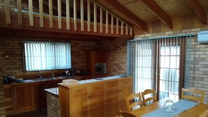 Eine Küche mit Holzausstattung, einer zentralen Kochinsel und einem Essbereich mit Tisch und Stühlen.