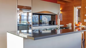 A modern kitchen with a stainless steel range hood, a glass backsplash, and a view of mountains through the window. - Woovim 14 by Interhome (Nendaz)