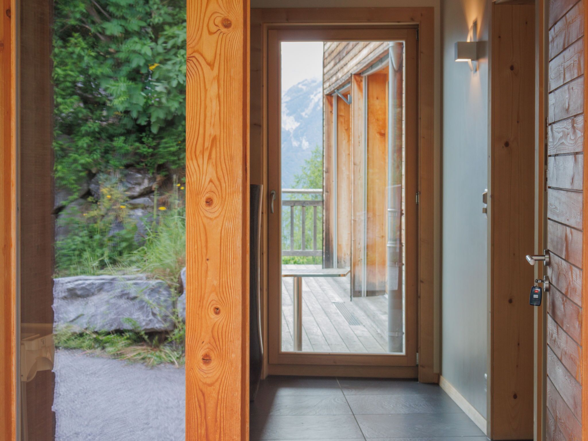 A wooden door leading to a balcony with a view of mountains.